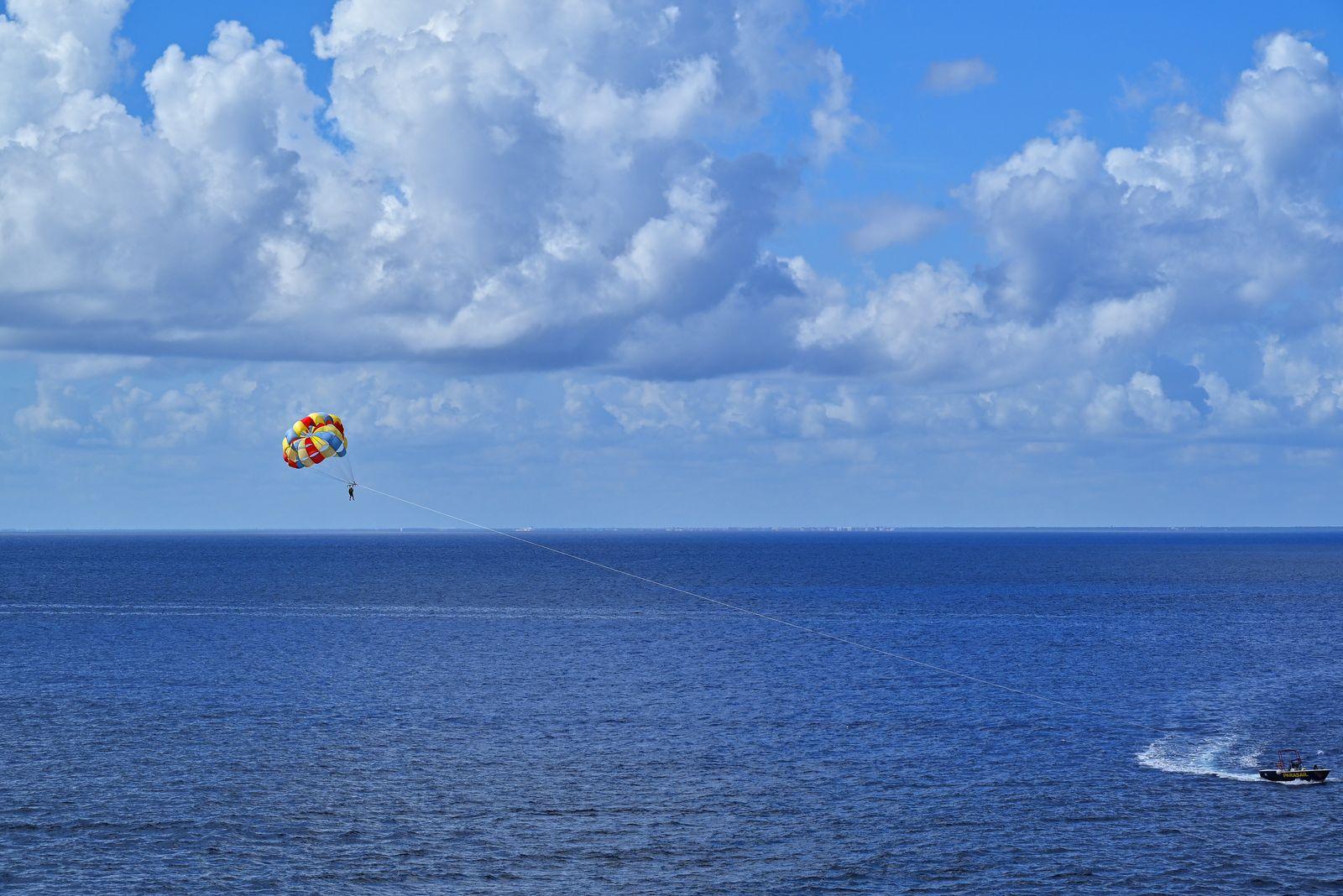 Parasailing above the blue sea behind a speedboat