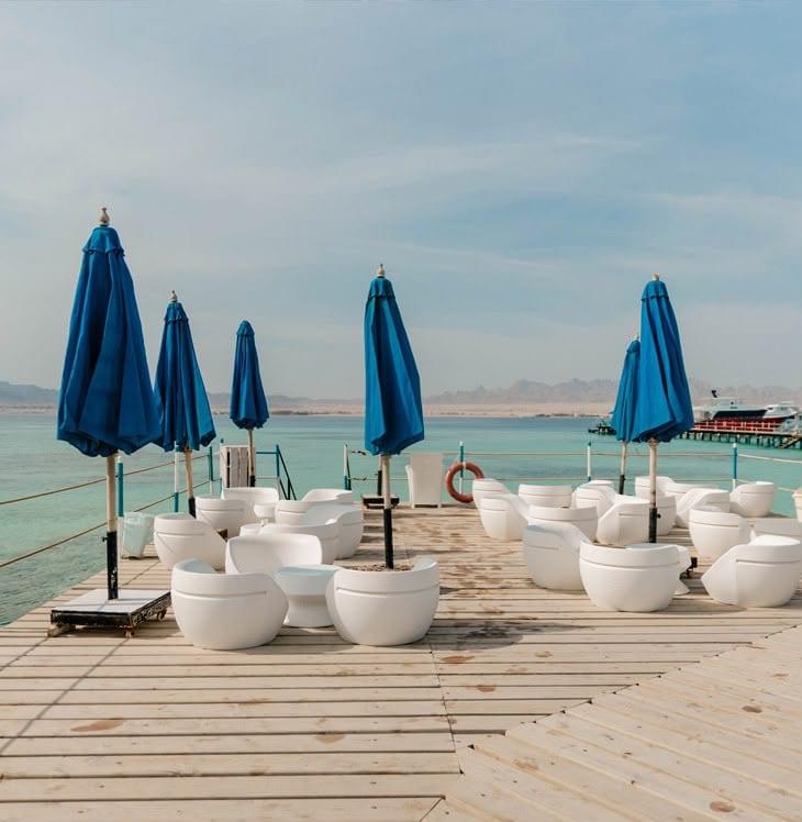 Blue parasols and white beanbag seats on the wooden deck at Bianca Island