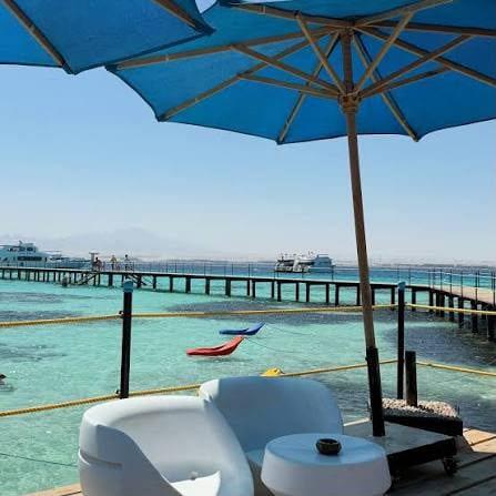 White loungers under a blue parasol beside the long wooden pier at Bianca Island