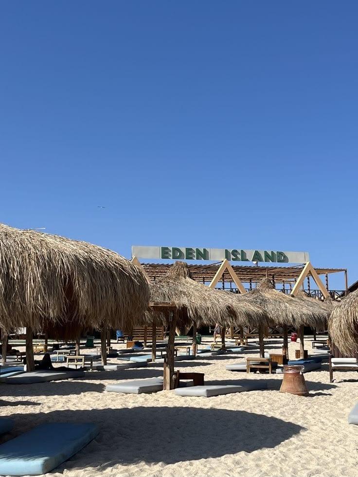 Eden Island sign above the straw parasols on the beach