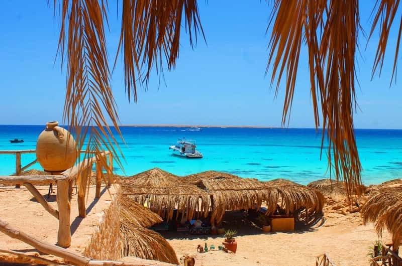 Straw shades and wooden seating overlooking the turquoise sea on Magawish Island