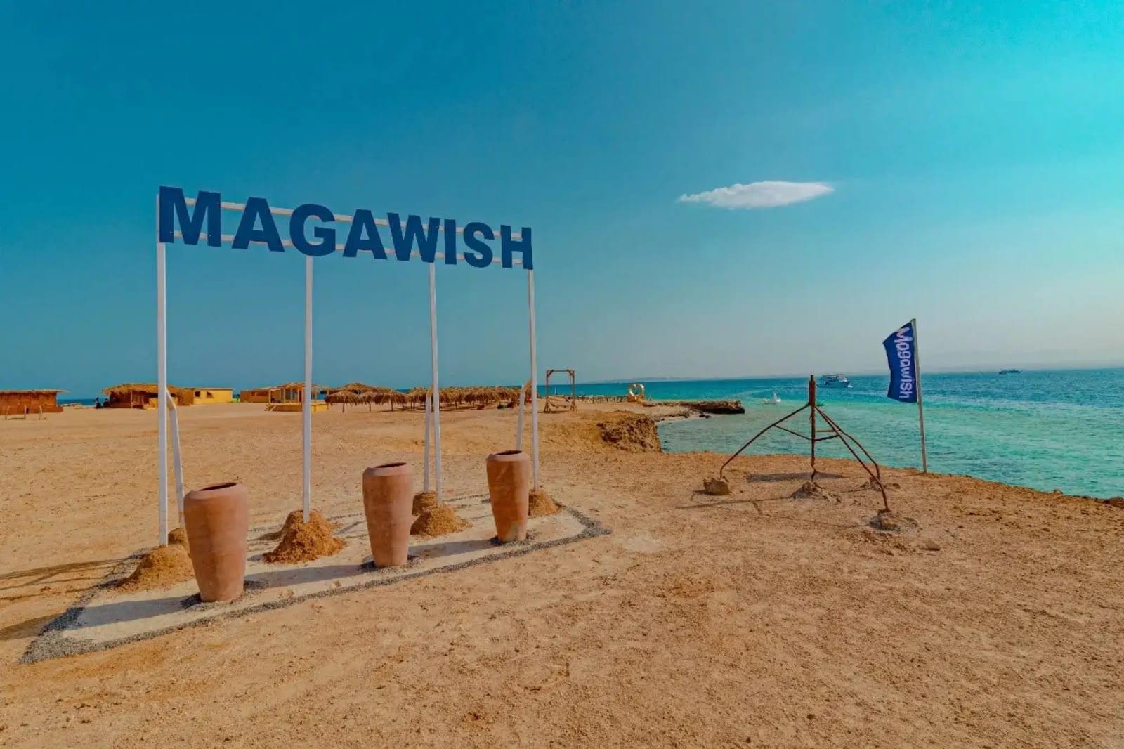 Magawish sign on the sandy beach by the turquoise sea