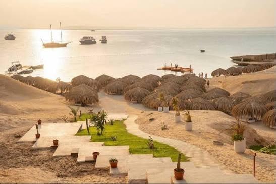 Sunset over the bay at Ozirea Island, with straw parasols on the sand and boats at anchor