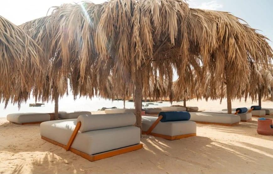 Lounge beds under a large straw parasol on the beach at Ozirea Island