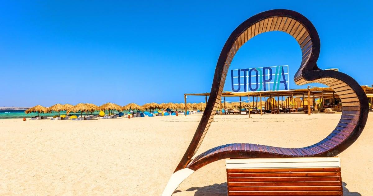 Heart-shaped wooden frame and the Utopia sign on the golden beach of Utopia Island