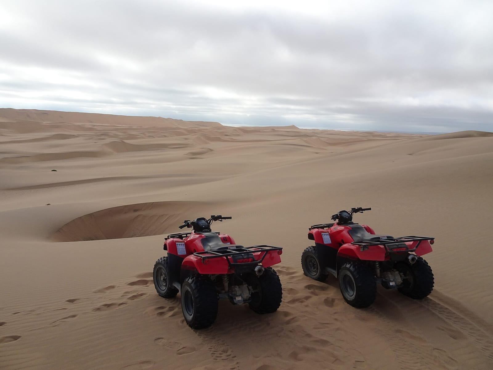 Red quad bikes parked on desert dunes